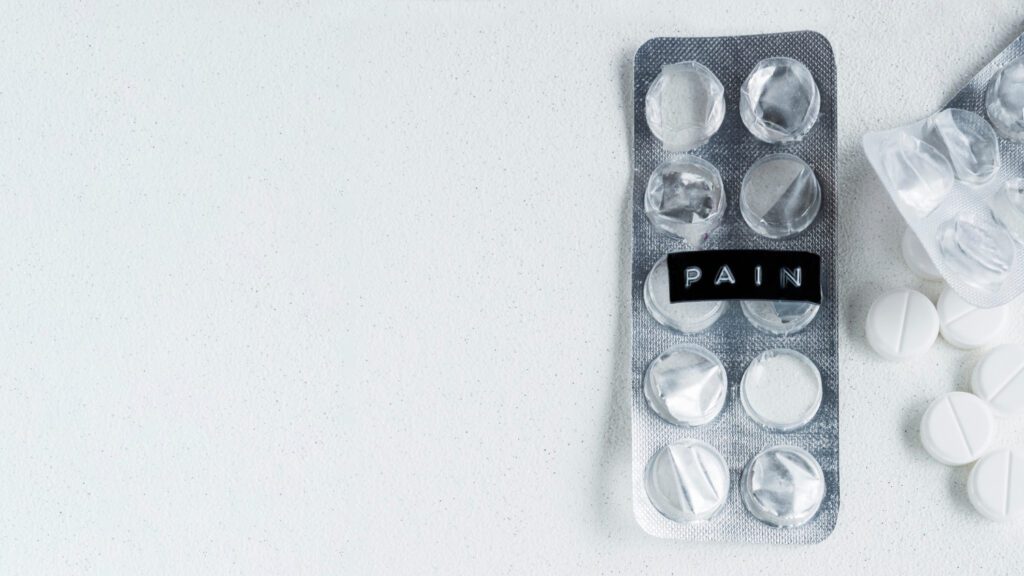Empty blister pack with the word 'PAIN' and white pain relief tablets scattered on a white background, emphasizing the necessity of pain management in emergencies.