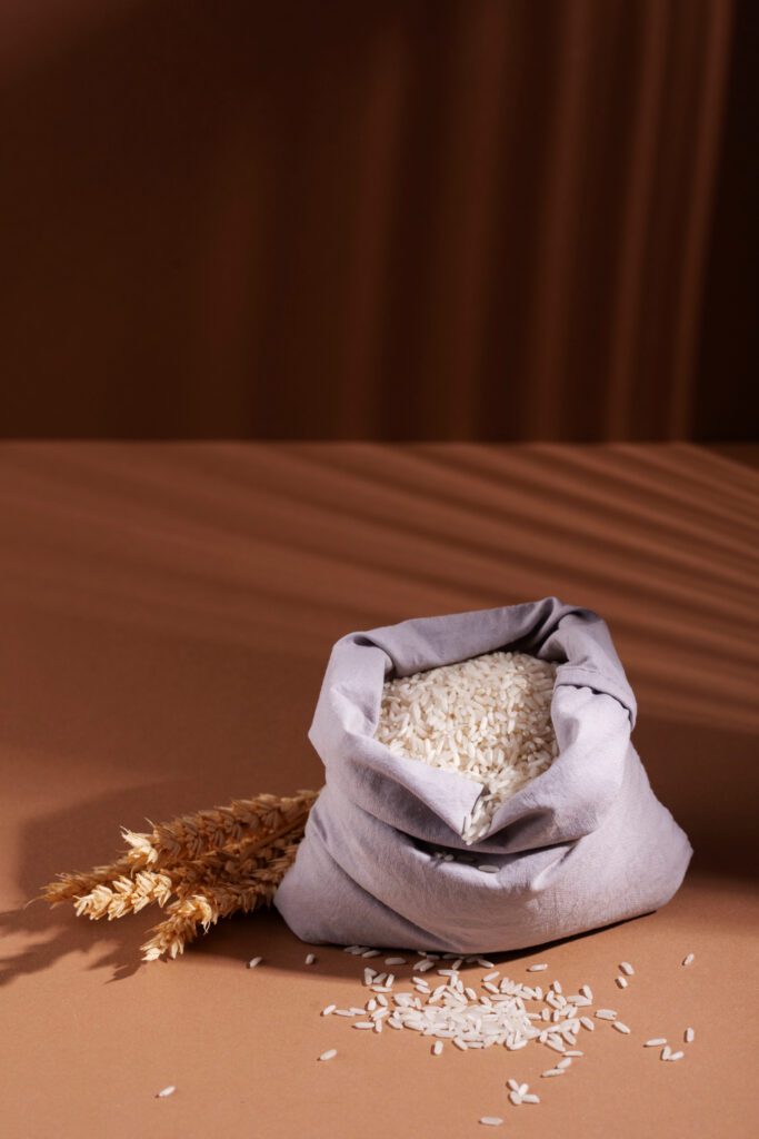 Bag of white rice on a brown surface with wheat stalks, symbolizing food storage and natural ingredients.