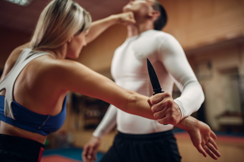 Woman performing self-defense technique against armed attacker.