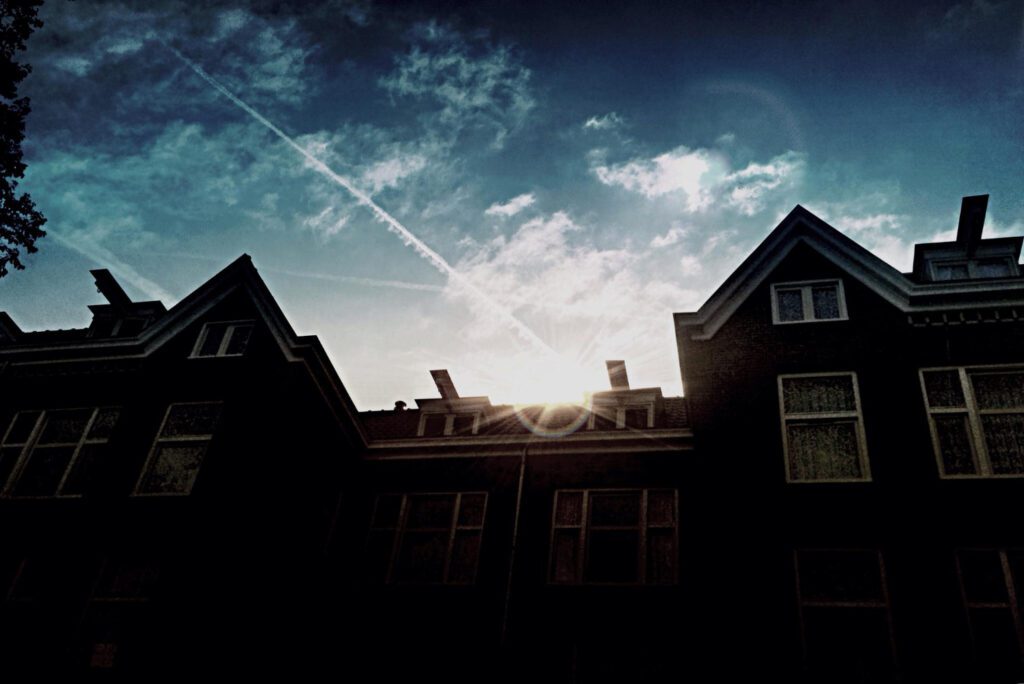 A dark silhouette of a house at sunset, with no visible lights, symbolizing a low-profile home strategy during a blackout.