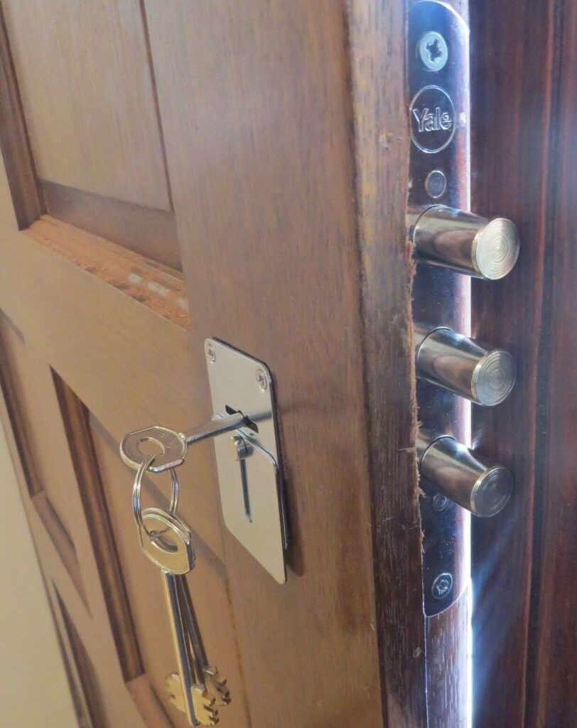 Close-up of a reinforced wooden door with a multi-bolt locking system and a key inserted in the lock, emphasizing home security.
