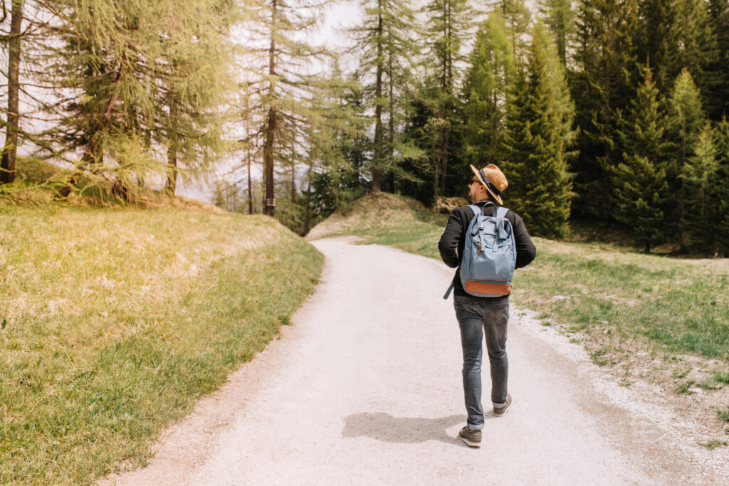 Solo hiker pausing on trail, considering direction in remote forest area