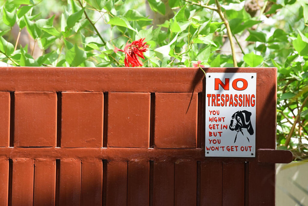 No trespassing sign with a dog warning on a residential wooden fence