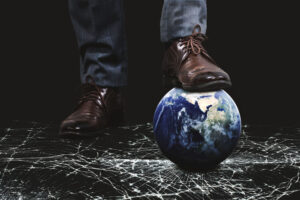 Man in dress shoes stepping on Earth, symbolizing global pressure and unseen threats
