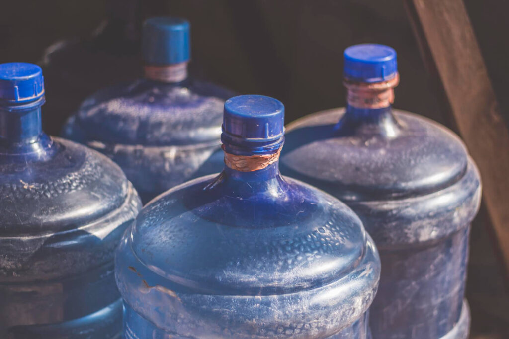 Large blue water storage jugs for emergency preparedness during blackouts.