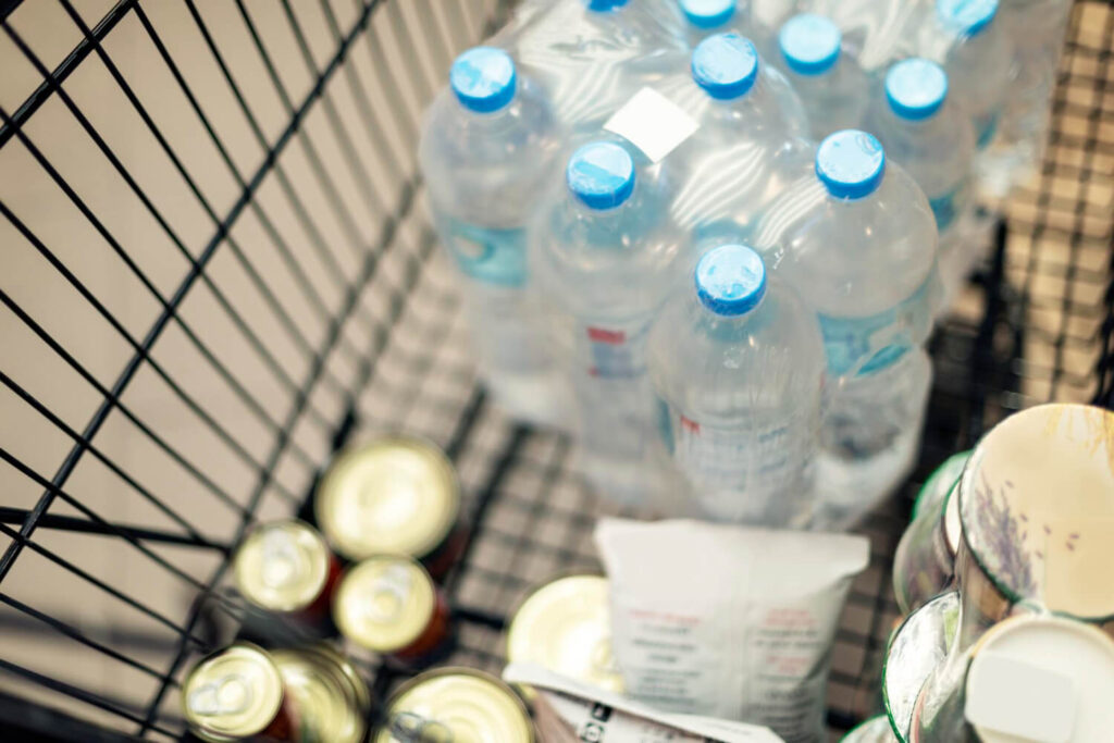 Shopping cart filled with bottled water and canned food, survival essentials during blackout panic buying.