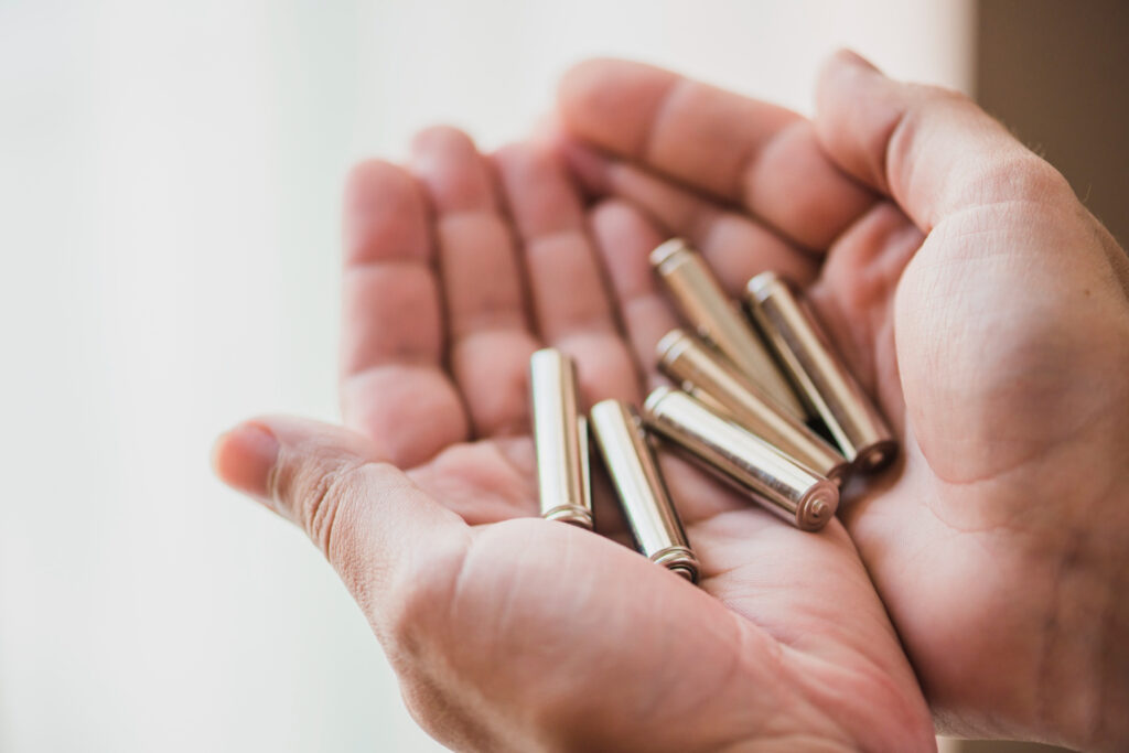 Hands holding batteries for survival during blackout power outage.