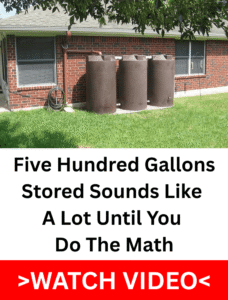 Three large brown rainwater storage tanks against a brick house connected to a downspout