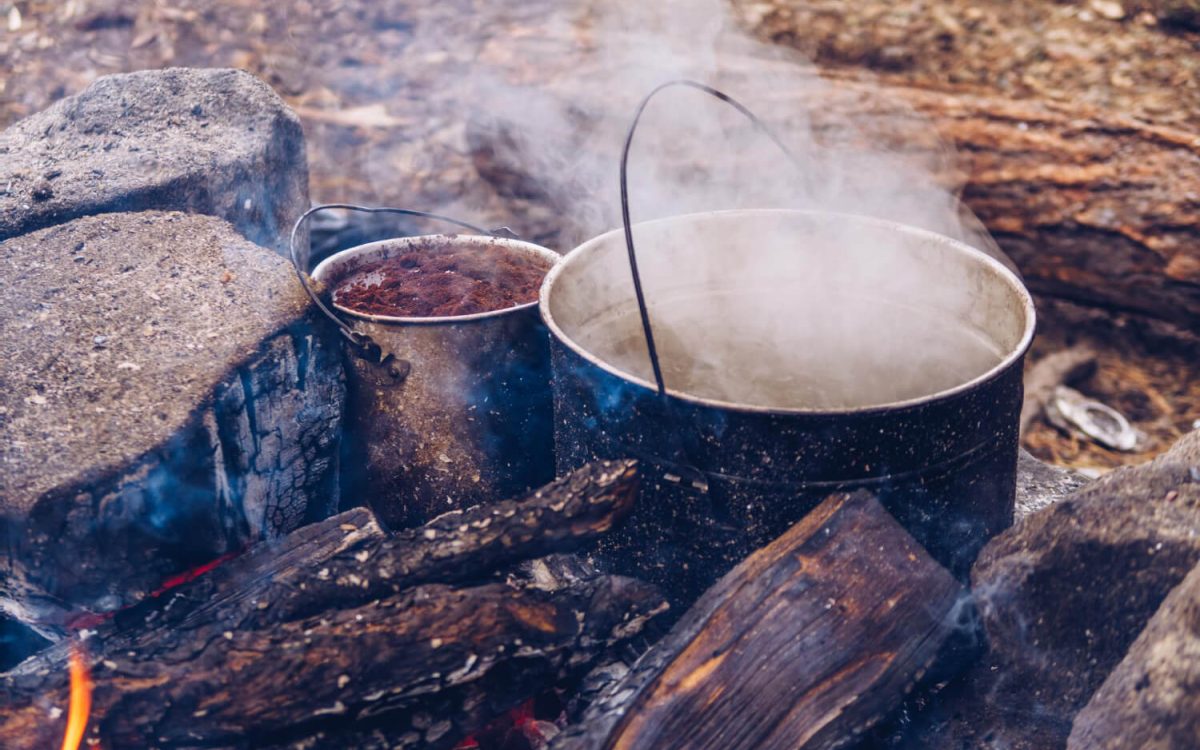 Boiling water over campfire in primitive pot for cook without power survival methods