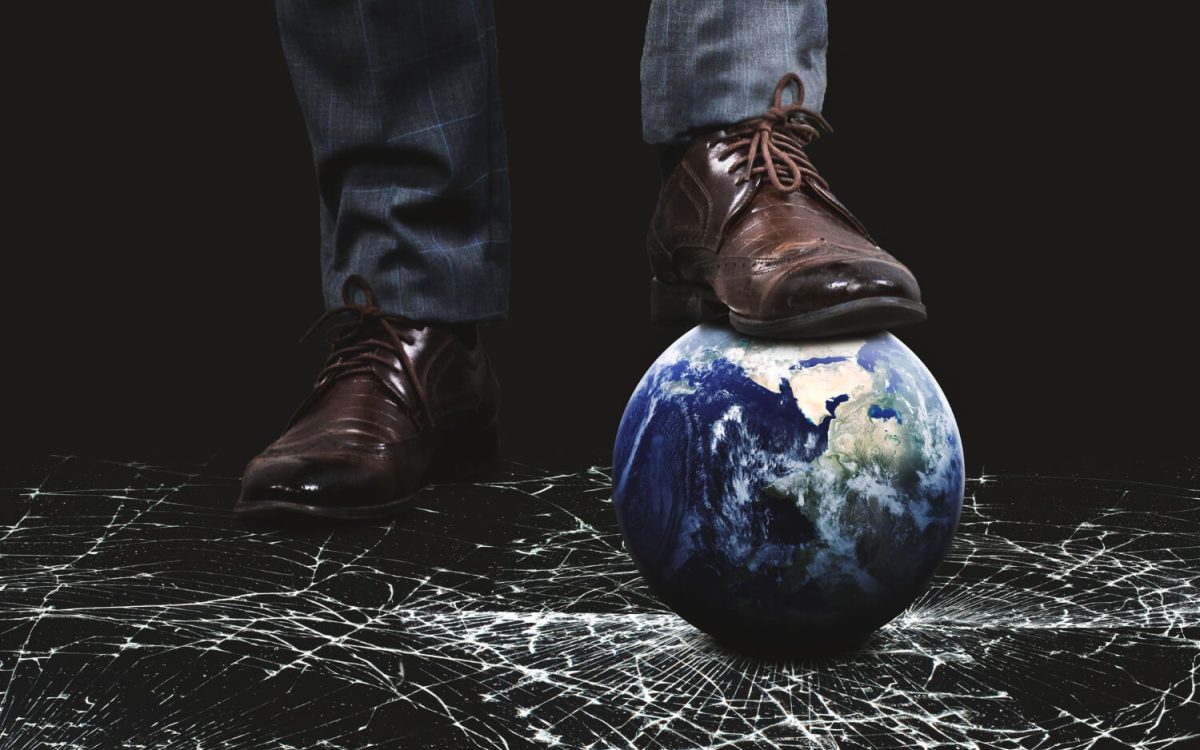 Man in dress shoes stepping on Earth, symbolizing global pressure and unseen threats