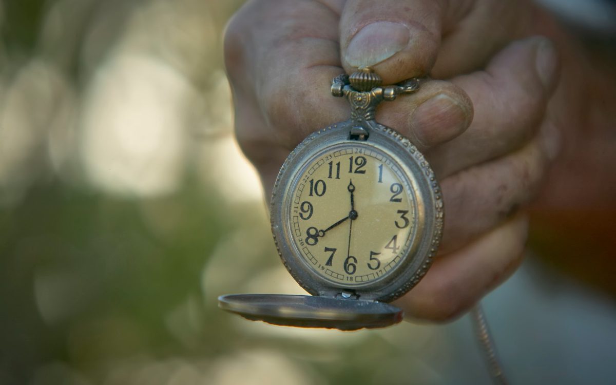 A close-up of a hand holding an antique pocket watch, symbolizing urgency and the need for last-minute prepping during emergencies.