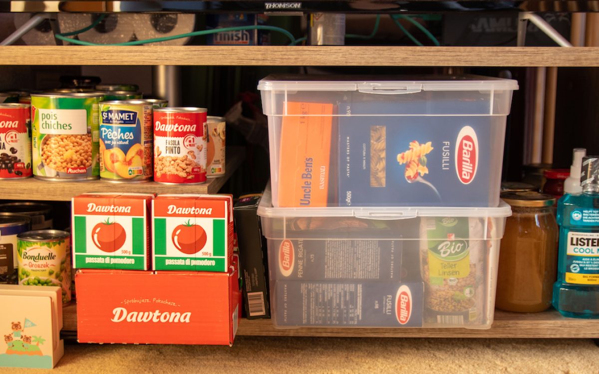 Apartment prepping storage with canned goods, pasta, and hygiene supplies organized on a shelf.